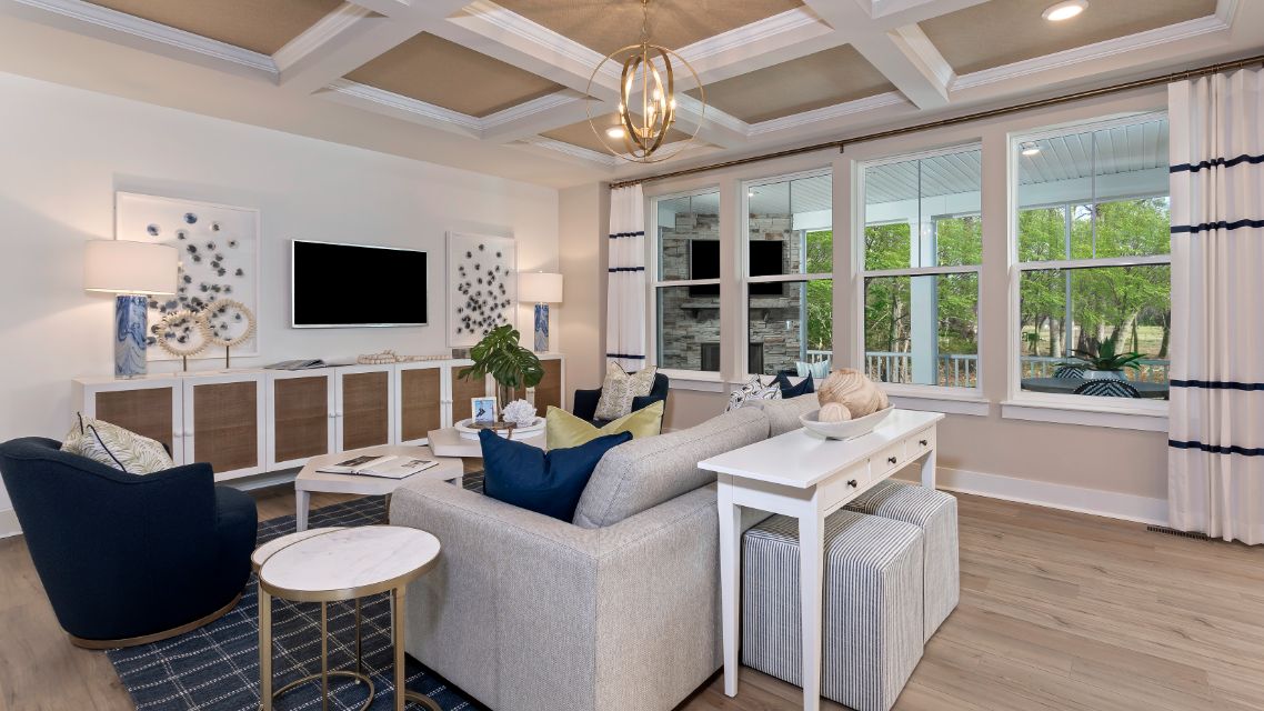Family room with coffered ceiling and wall of windows in a DRB Homes Barbados model home in The Estuary community.