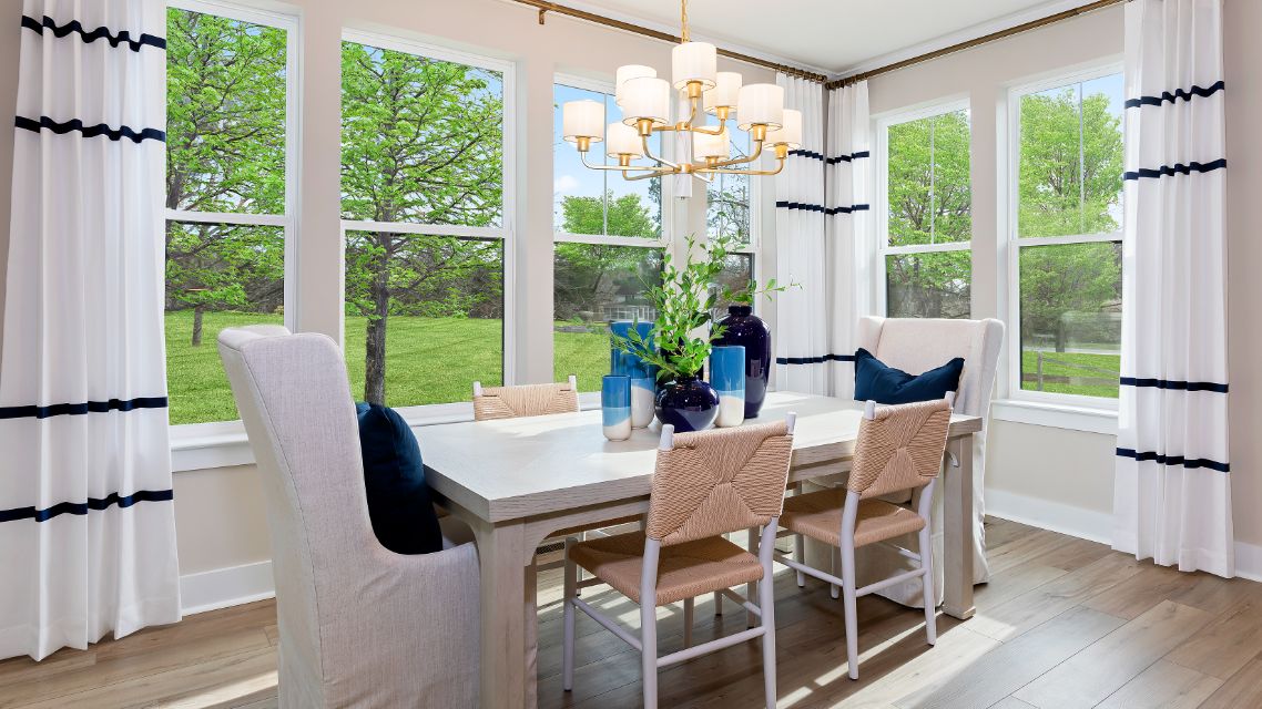 Dining area surrounded by large windows and light wood floors  in a DRB Homes Barbados model home in The Estuary community.