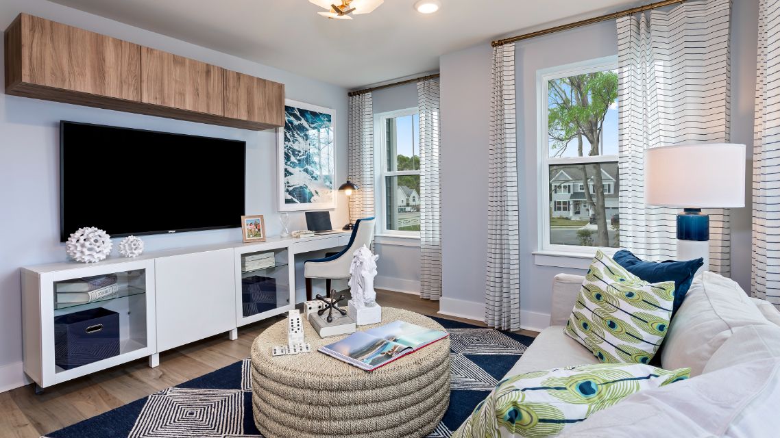Family room with seating and two large windows in a DRB Homes Barbados model home in The Estuary community.