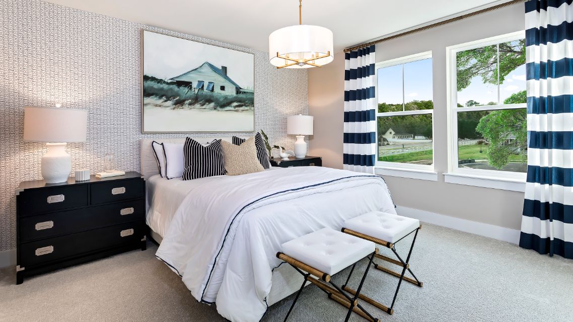 Secondary bedroom with wall to wall carpet & 2 large windows in a DRB Homes Barbados model home in The Estuary community.