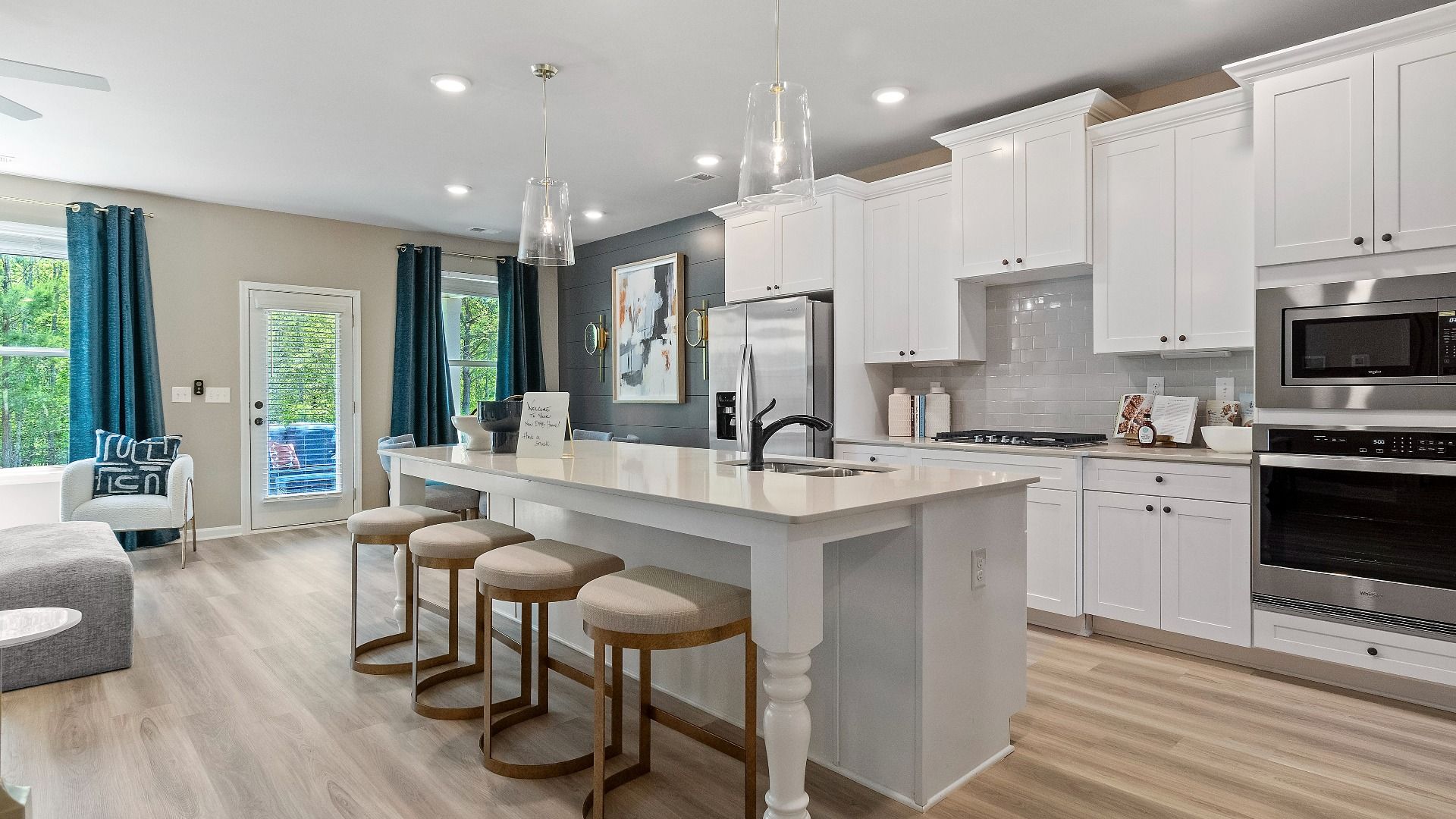 Open kitchen featuring center island, white cabinets, and tile backsplash at Kingston in Locust Grove, GA.