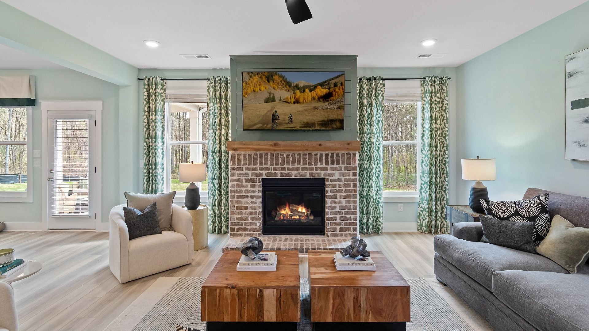 Open family room with large windows and a gas fireplace with brick design at Saddleridge in Senoia, GA.