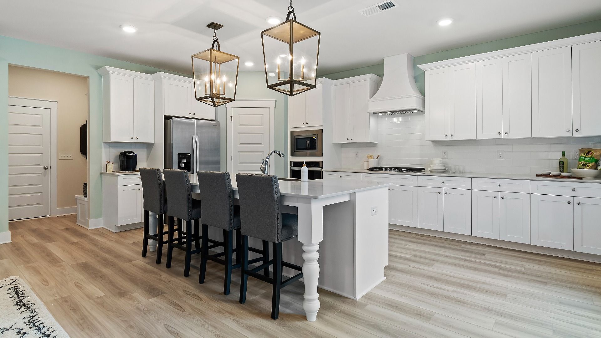 Modern kitchen with abundant white cabinetry, large island, and stainless steel appliances at Saddleridge in Senoia, GA.