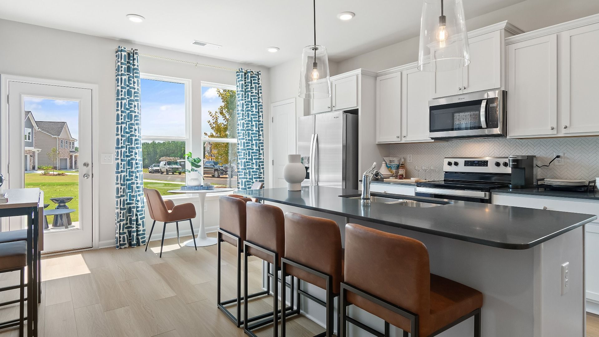 Open kitchen with island seating, stainless appliances, and pendant lighting at Westminster in Covington, GA.