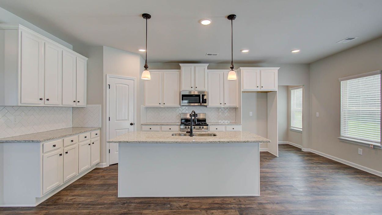 Bright modern kitchen with abundant cabinetry, center island, and pendant lighting in the Vickery at Berkeley Lakes.