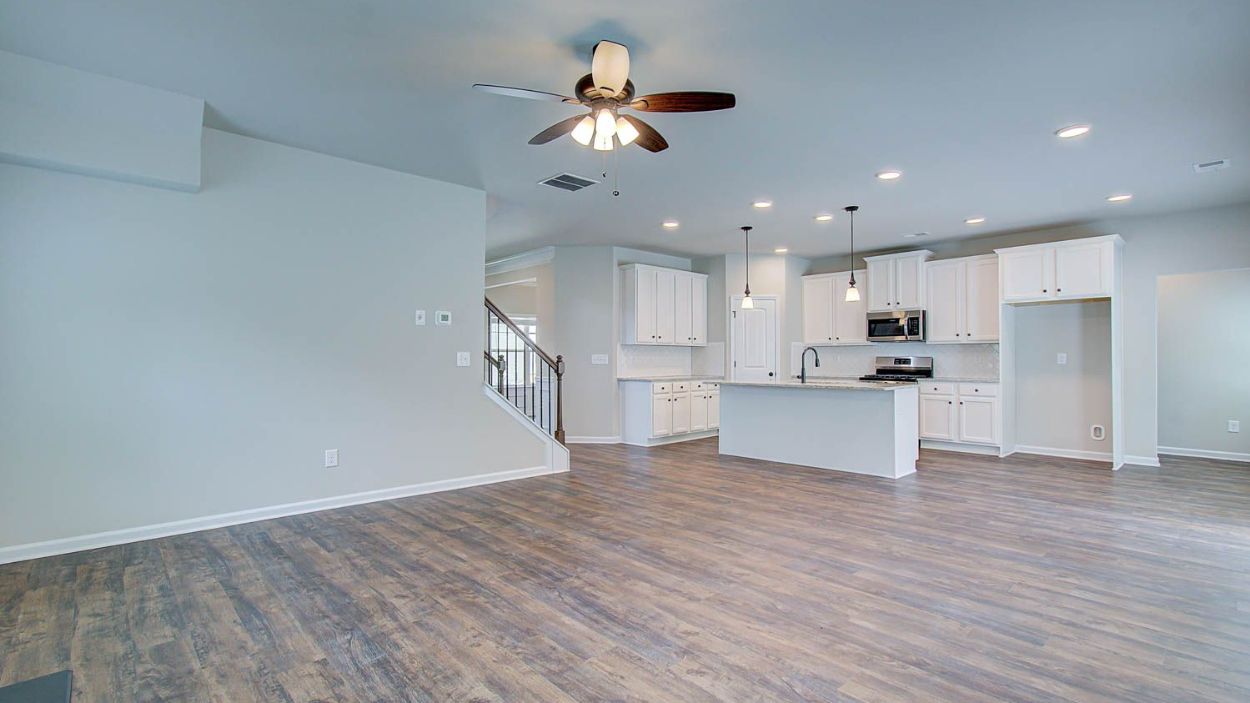Open family room with LVP flooring, natural light, and view to kitchen in the Vickery at Berkeley Lakes in Locust Grove, GA.