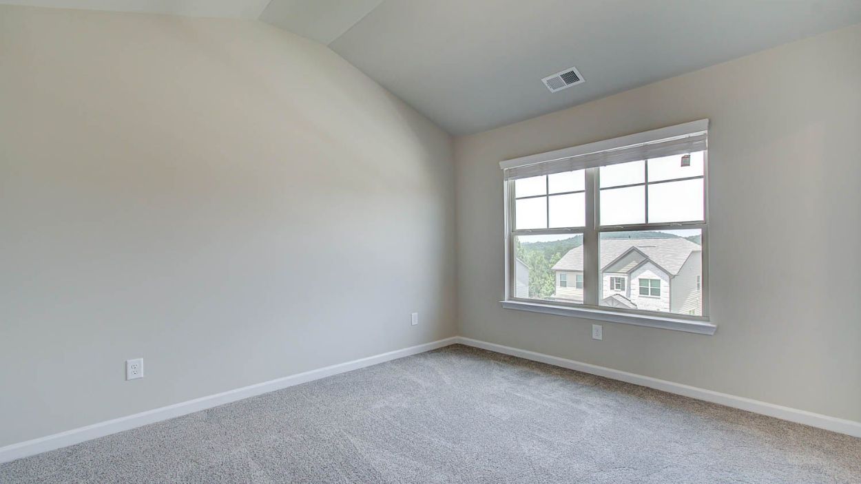 Second level secondary bedroom with carpet flooring and natural light in the Vickery at Berkeley Lakes in Locust Grove, GA.