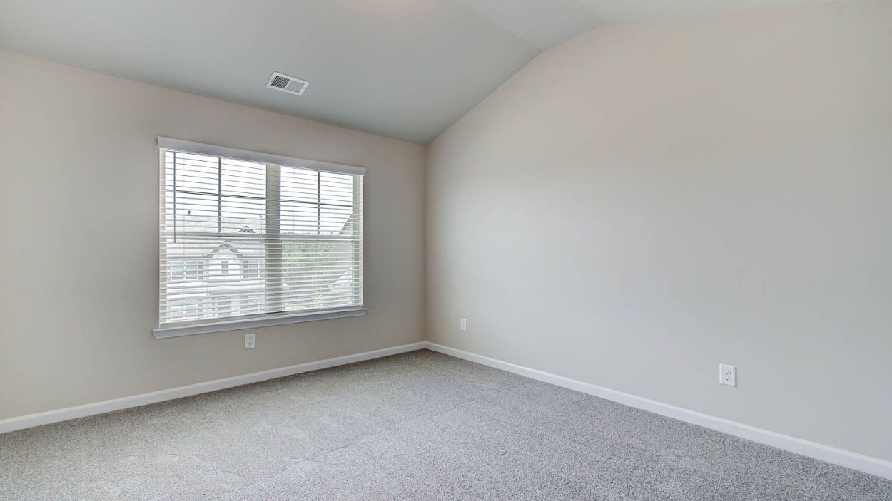 Spacious primary suite with carpet flooring and large window in the Vickery at Berkeley Lakes in Locust Grove, GA.