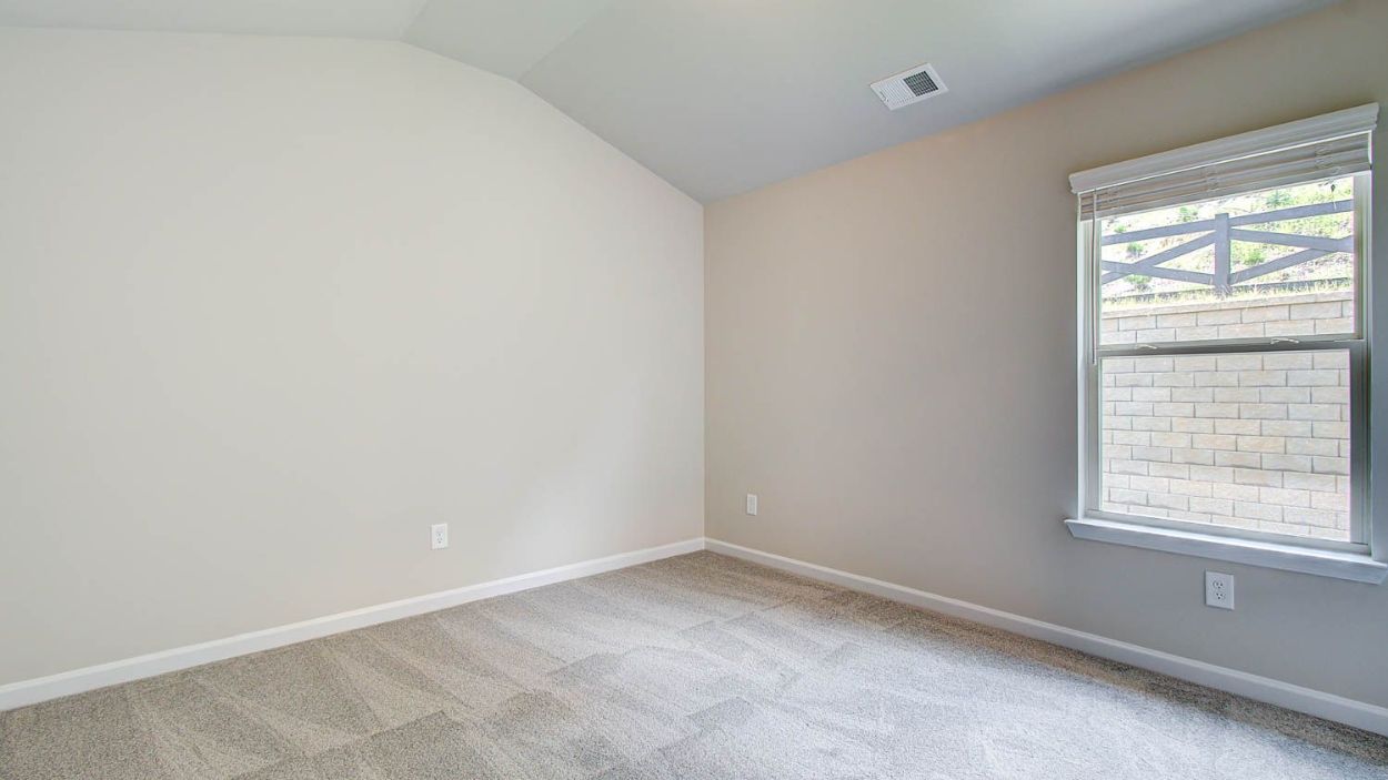 Cozy secondary bedroom with carpet flooring and natural light in the Vickery at Berkeley Lakes in Locust Grove, GA.