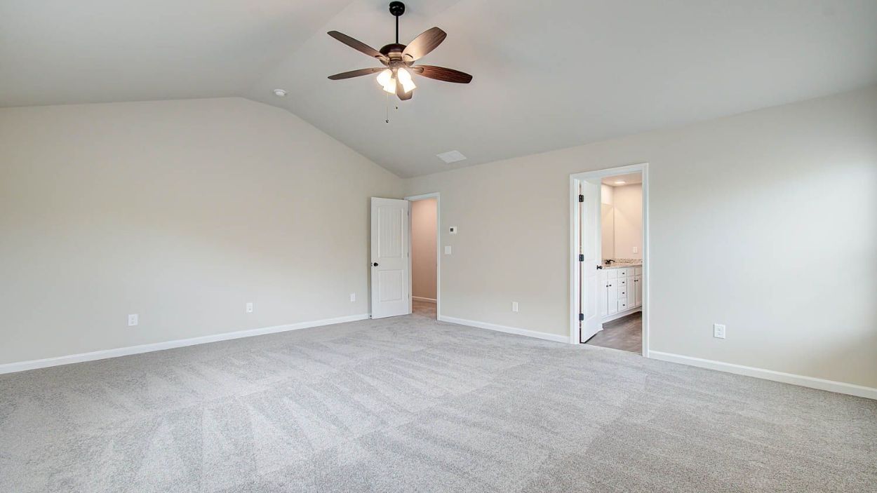 Expansive primary suite with carpet flooring, natural light, and connecting bath in the Vickery at Berkeley Lakes.