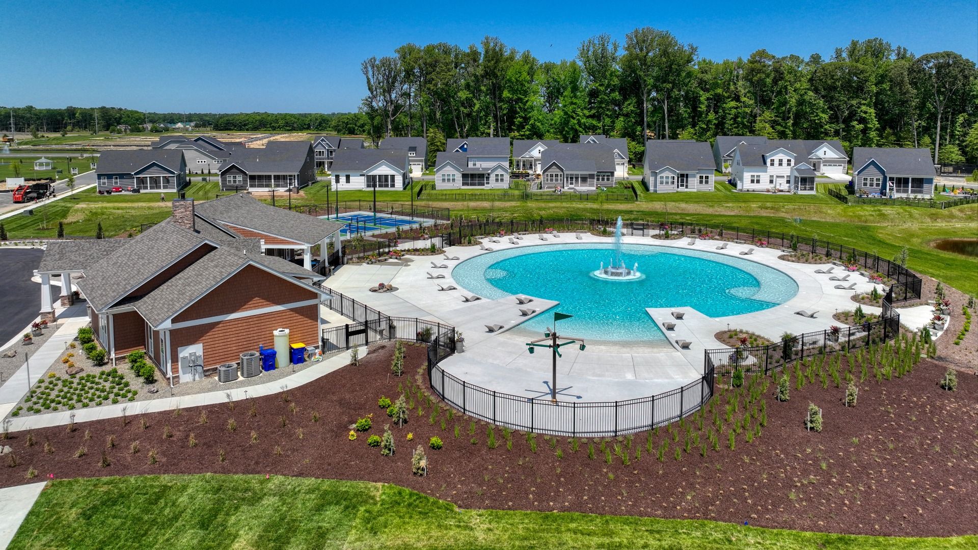 Circular shaped pool with fountain and clubhouse at the DRB Homes community of Chase Oaks in Lewes, Delaware.