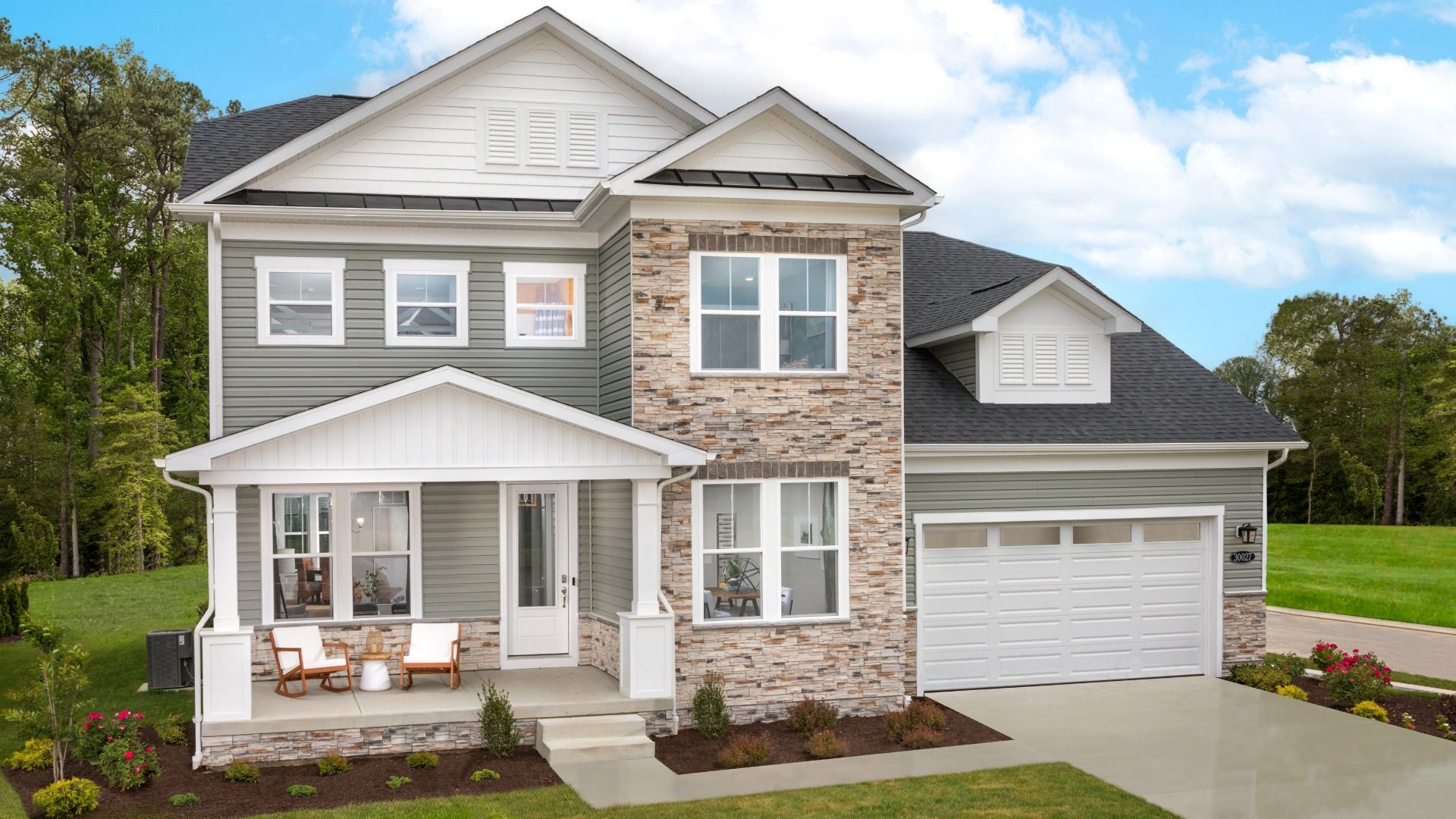 Single-family home with tan stone water table, large windows, porch, and white front two car garage at Delaware Beaches.