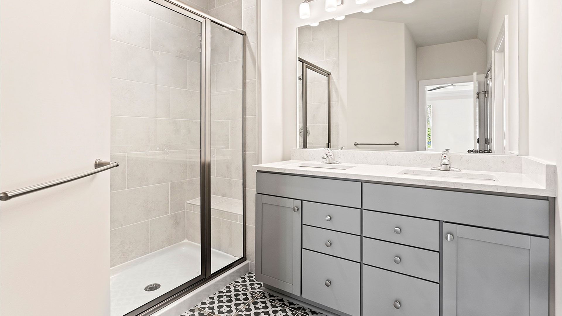 Owner's bathroom with gray, dual sink vanity and walk-in, tiled shower in a DRB Homes Latitude home.