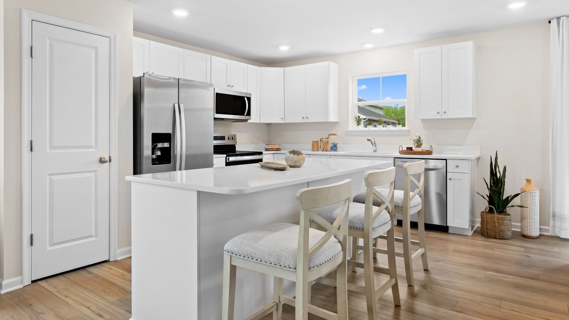 Island kitchen with white cabinets in a DRB Homes Whitehall Model at the Village of College Park community.