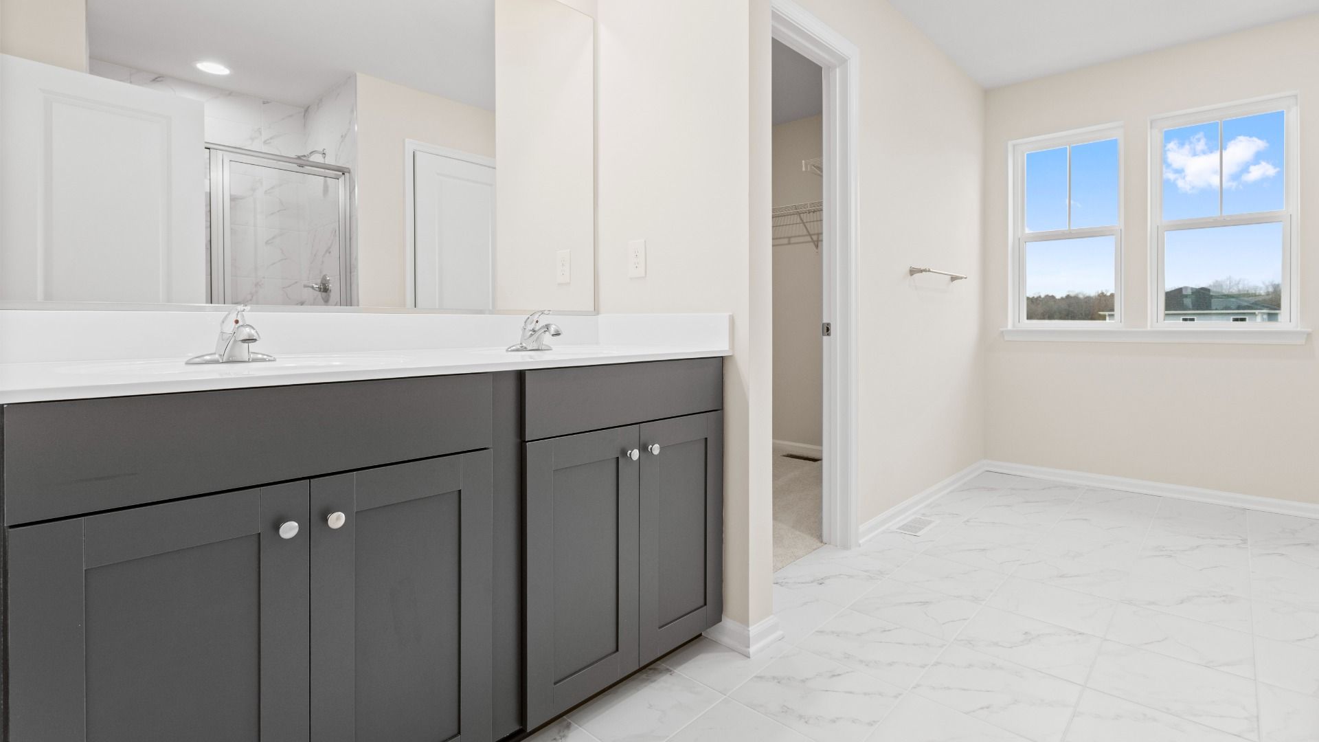 Owner's bath with gray dual sink vanity and double window in a DRB Homes Glenshaw plan at The Village of College Park.