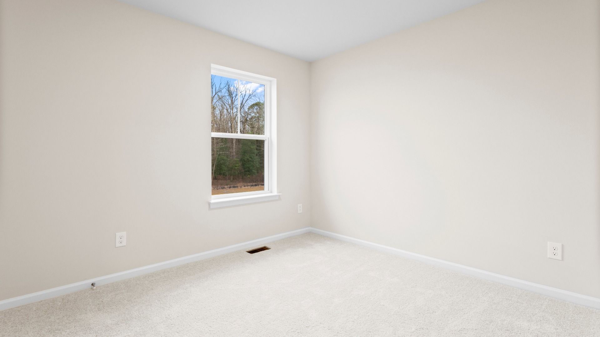 Carpeted secondary bedroom with large window in a DRB Homes Glenshaw plan at The Village of College Park.