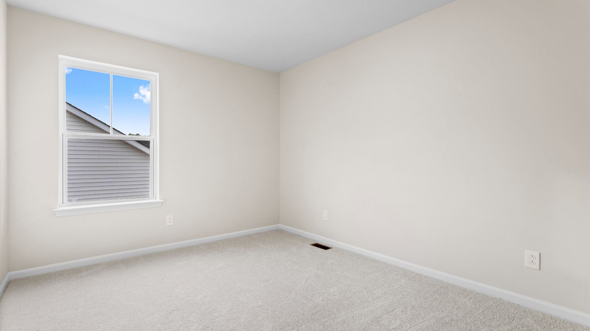Carpeted secondary bedroom with large window in a DRB Homes Glenshaw plan at The Village of College Park.