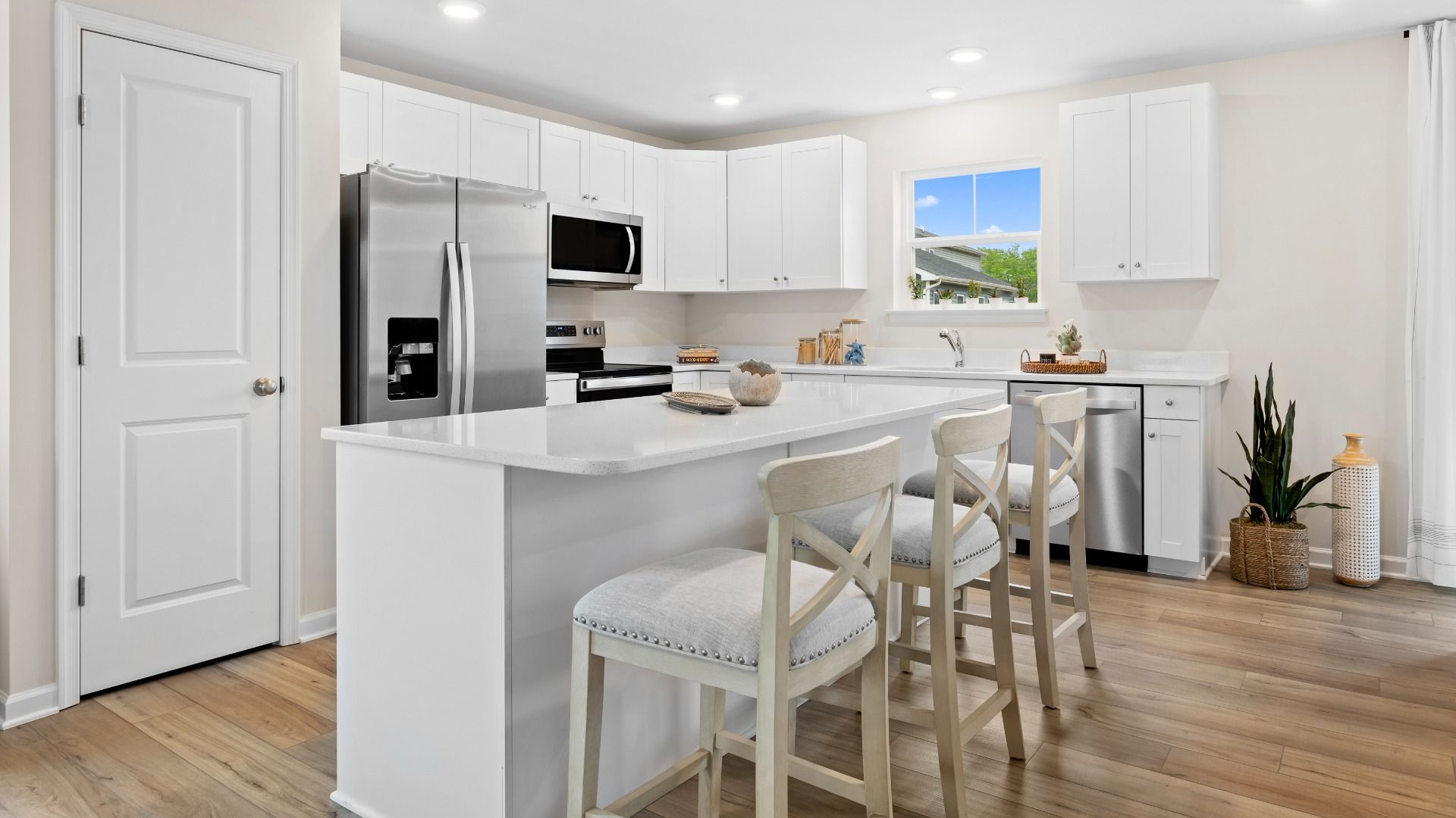Island kitchen with white cabinets in a DRB Homes Whitehall Model at the Village of College Park community.