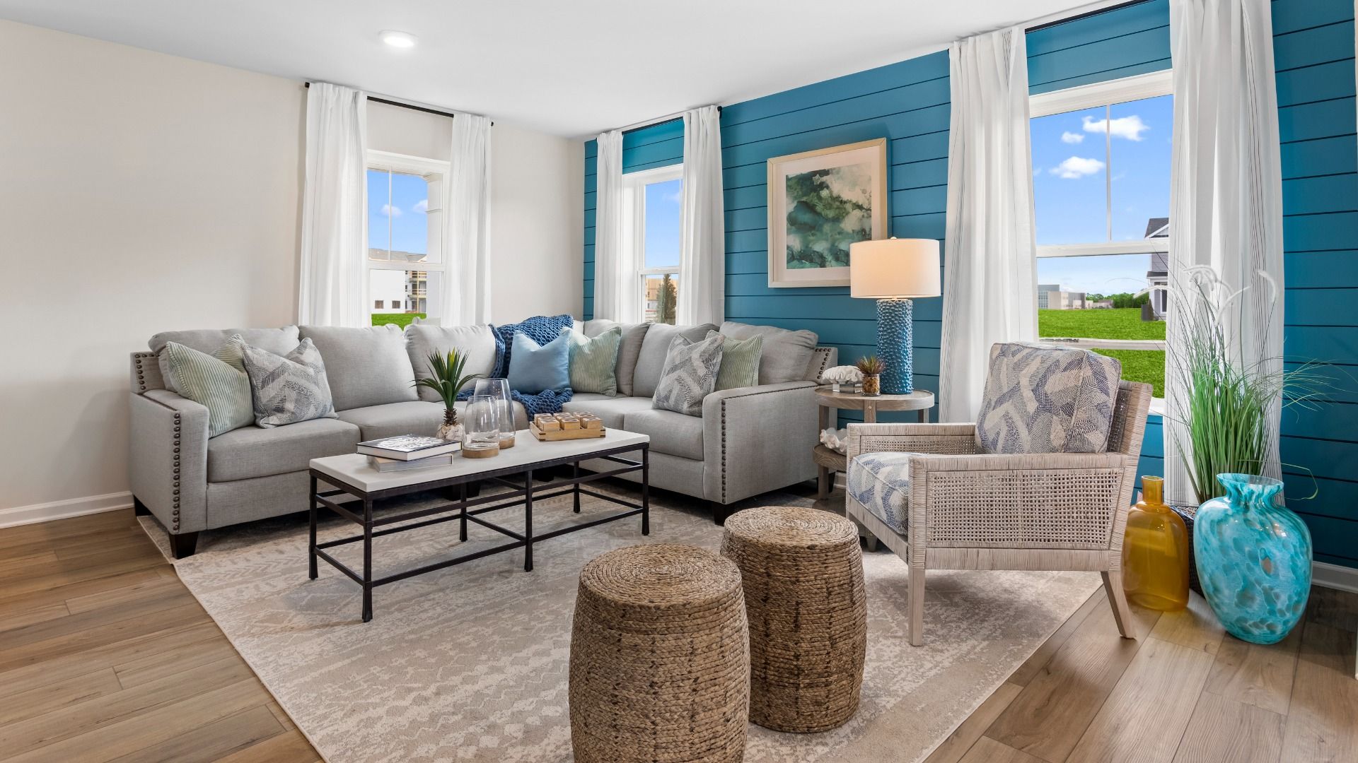 Living room with seating and 3 large windows in a DRB Homes Whitehall Model at the Village of College Park community.