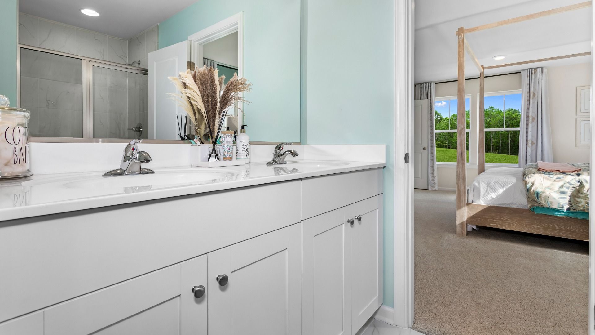 Owner's bath with white dual sink vanity in a DRB Homes Whitehall Model at the Village of College Park community.