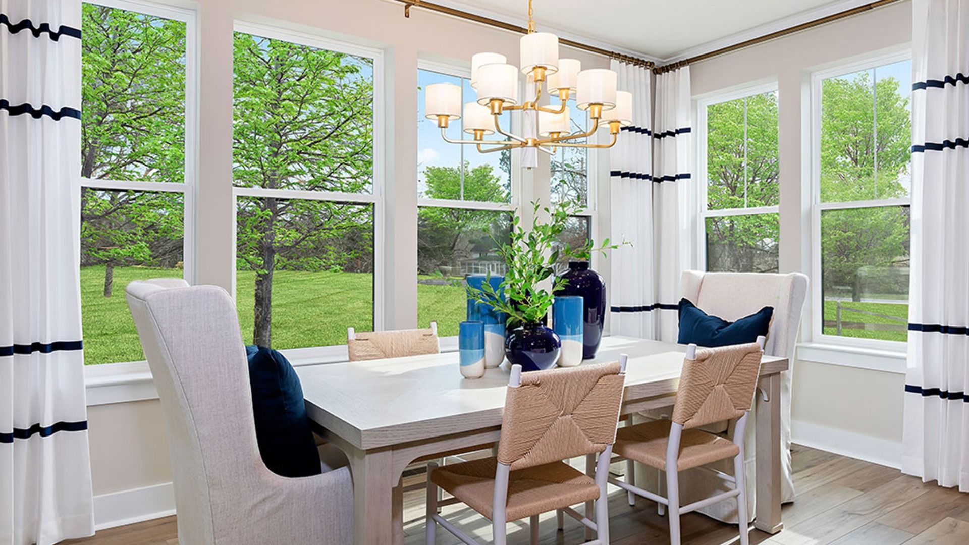 Dining area with light wood floors, 4 windows on back wall and 2 large windows on adjacent wall.