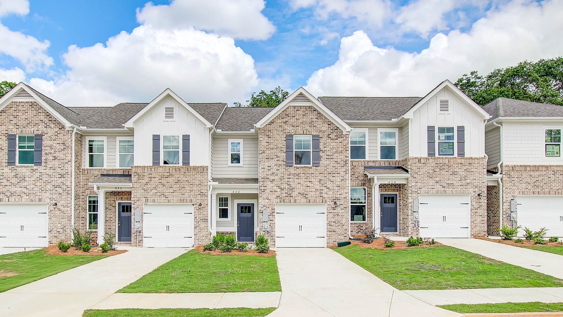 New construction townhome with brick accents and attached garage at Avery Landing in McDonough, GA
