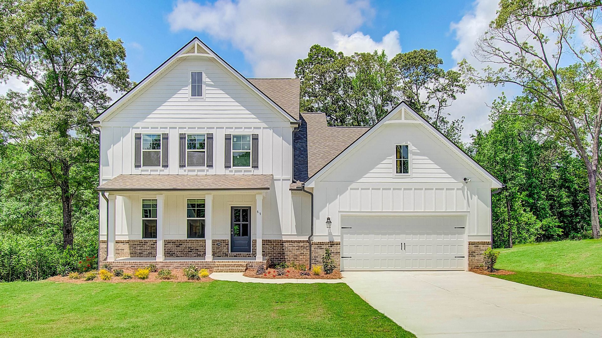 Two-story single-family home exterior with covered front porch and two-car front entry garage at Saddleridge in Senoia, GA.