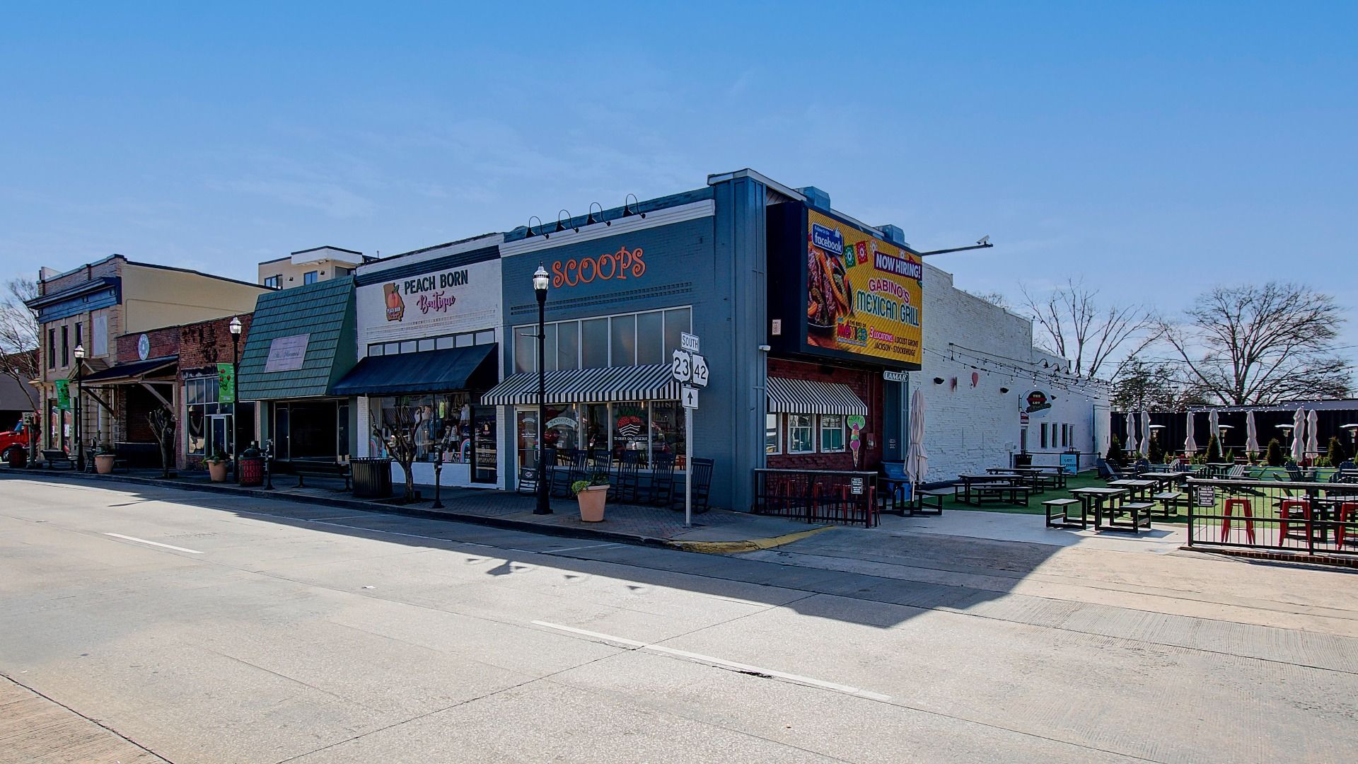 Downtown strip featuring Scoops ice cream, Peach Born Boutique, and greenspace in McDonough, GA near Silverock community.