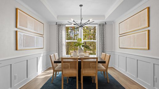Luxurious formal dining room with tray ceiling and large windows. The Jordan Plan at Lakeside Glen in York, SC, by DRB Homes