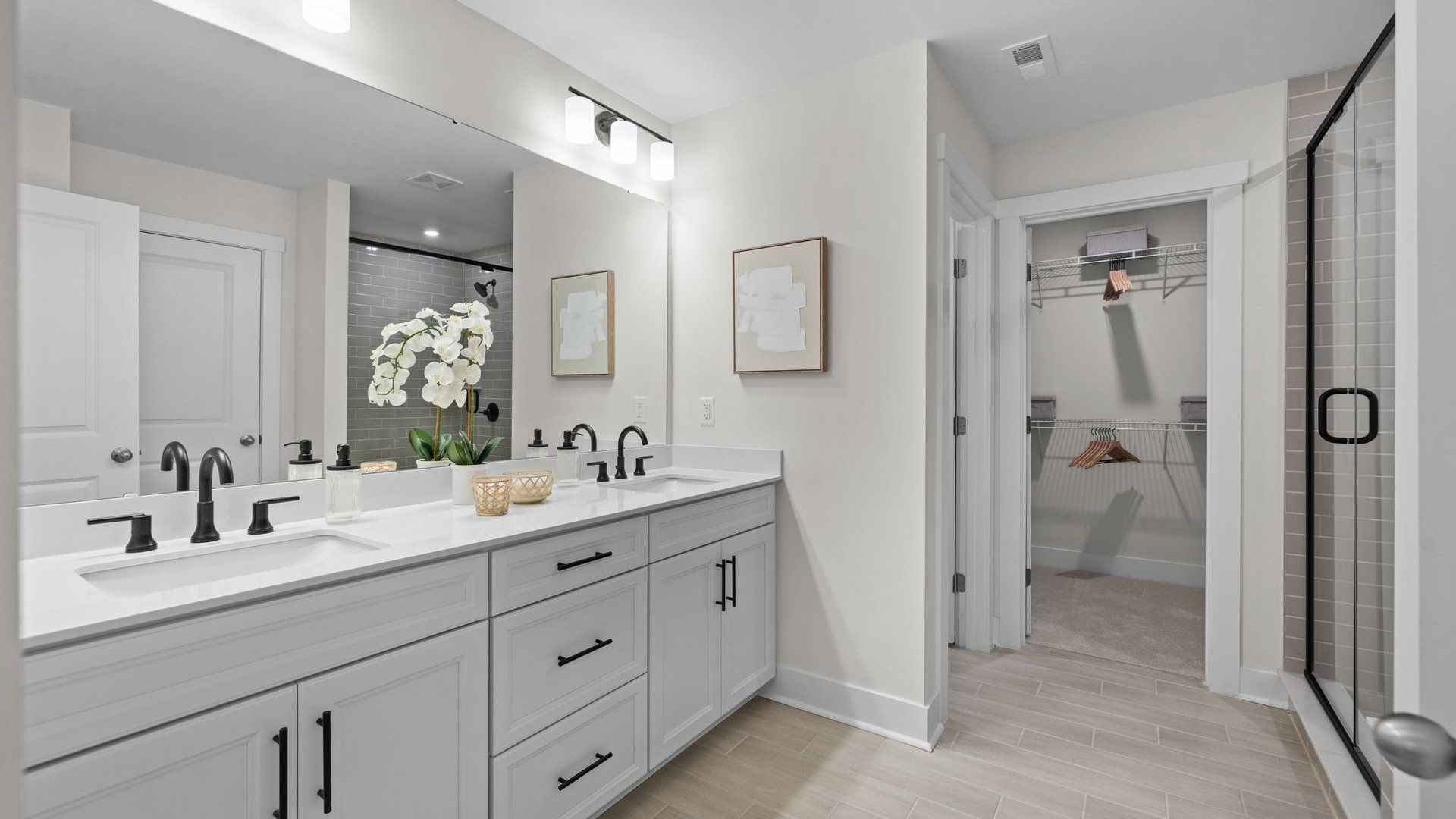 Primary bathroom offers spacious dual vanity, ample storage, private water closet, tiled shower, and large walk-in closet.