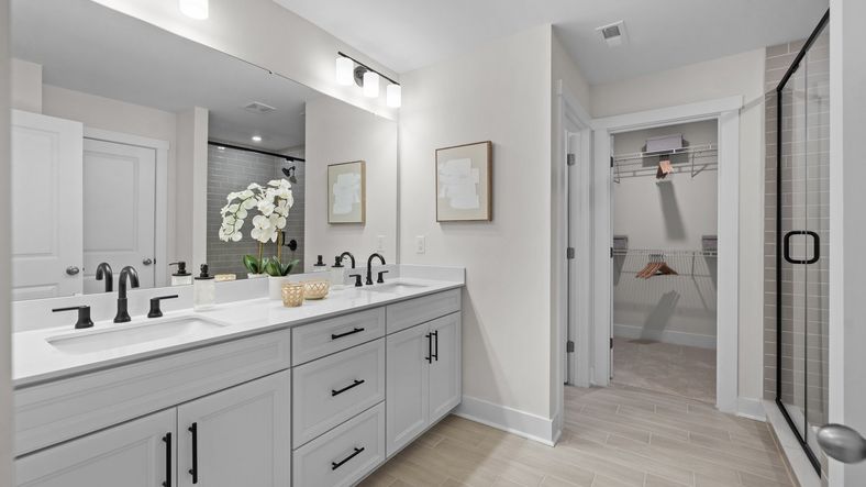 Primary bathroom offers spacious dual vanity, ample storage, private water closet, tiled shower, and large walk-in closet.