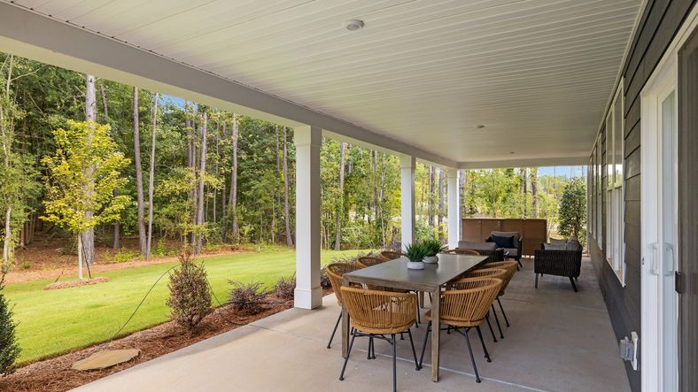 Large covered rear porch with backyard views and spaces for outdoor dining & seating. Lakeside Glen. DRB Homes. York, SC.