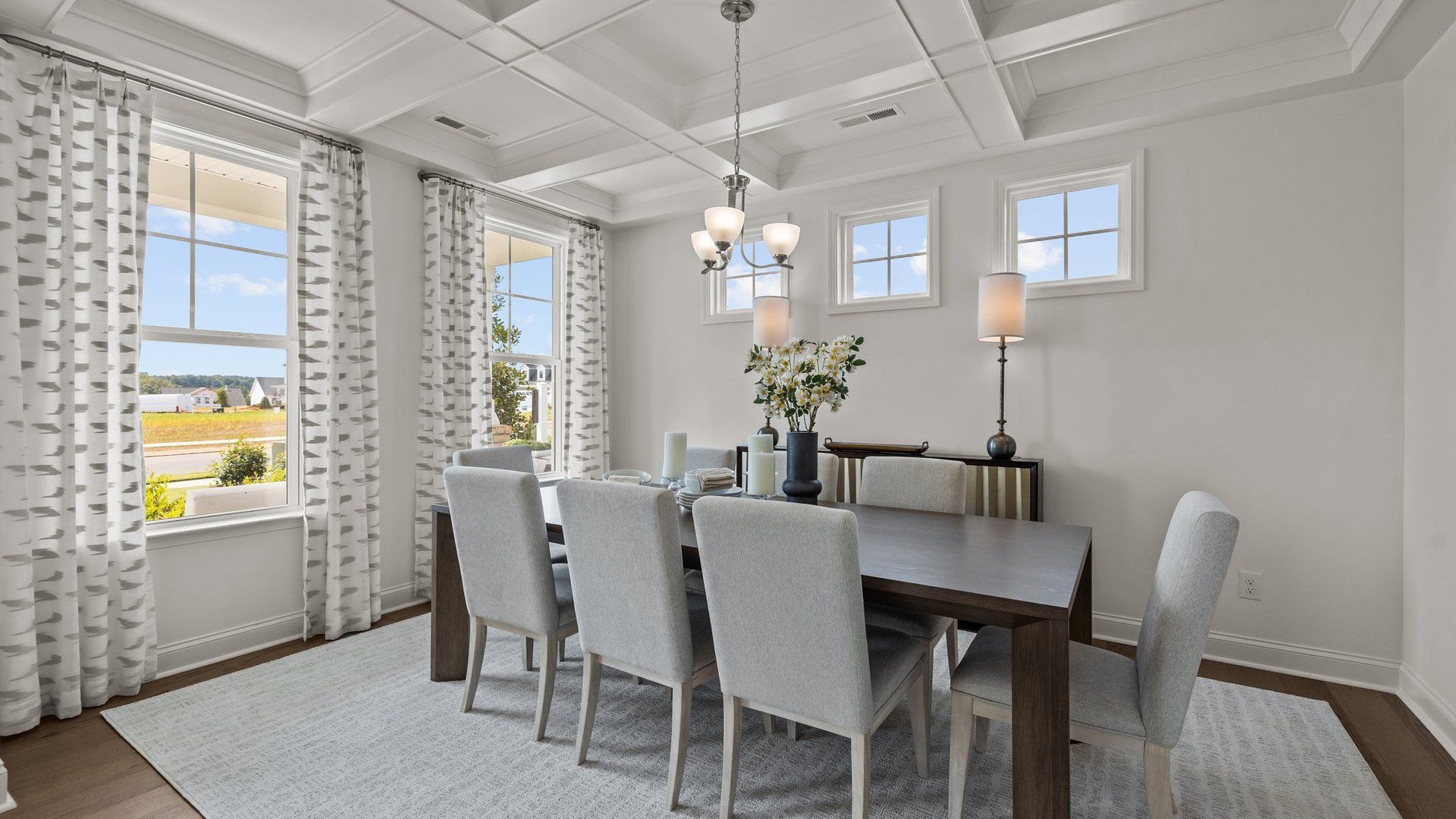 Bright and luxurious dining room with raised coffered ceiling and plentiful windows, in the Townsend Design by DRB Homes