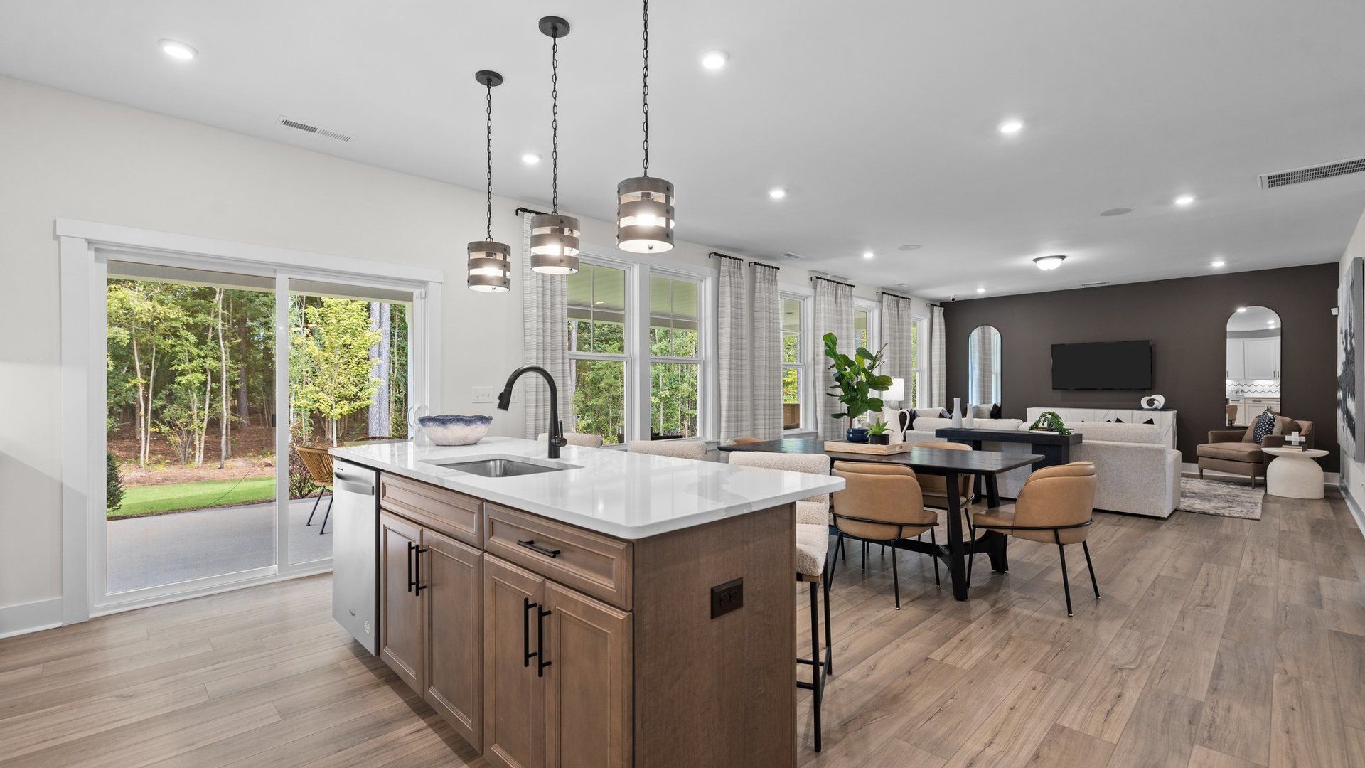 Open concept kitchen island, eat-in breakfast, and family room with abundant windows, in the Jordan Design by DRB Homes