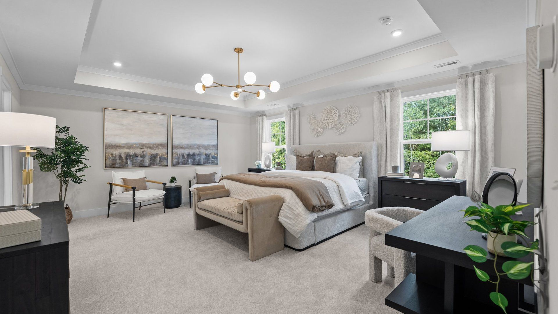 Grand primary bedroom with seating area, elevated tray ceiling, & large windows in the Jordan Design by DRB Homes in York, SC