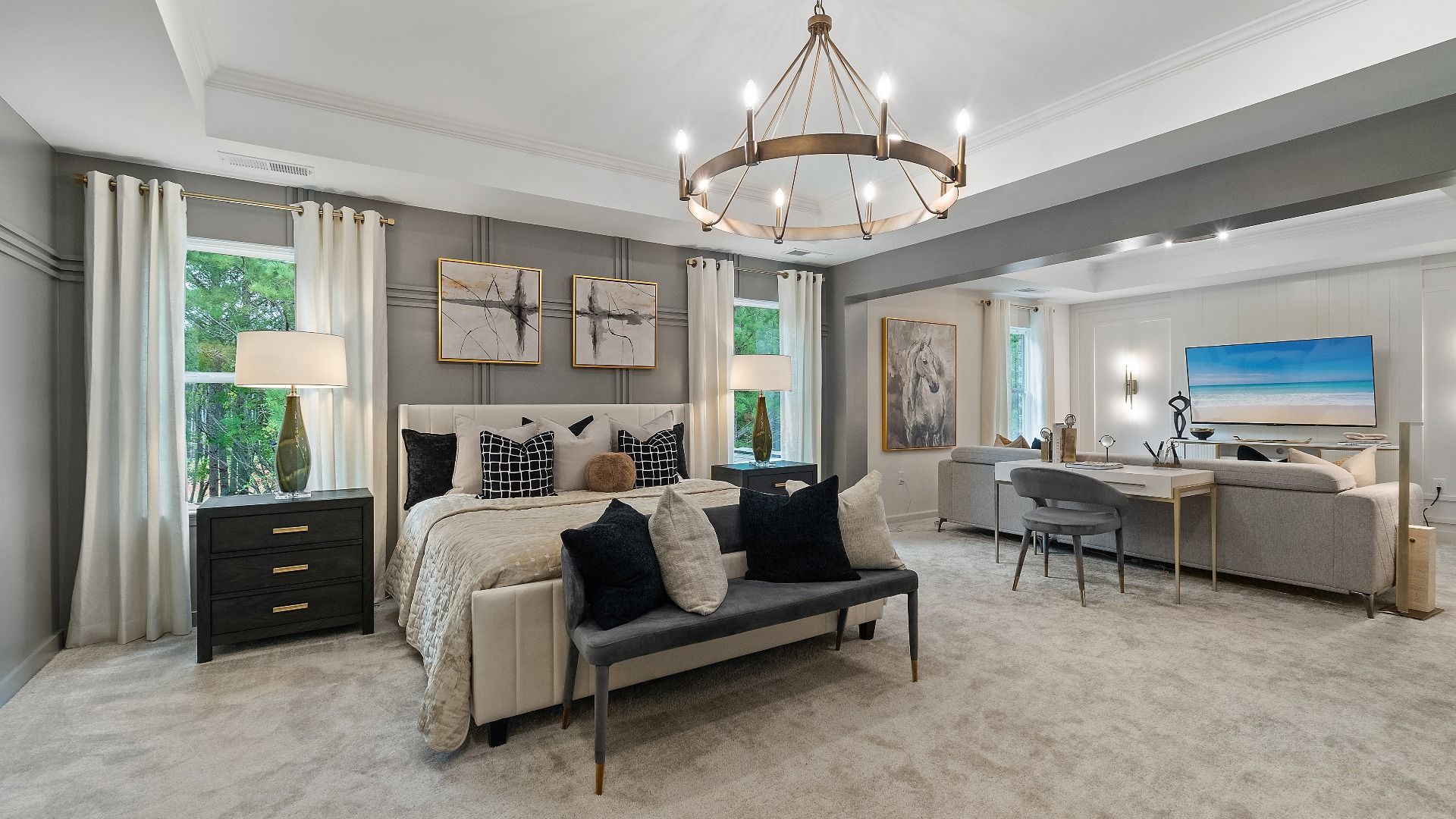Expansive primary suite with comfortable seating area, tray ceiling, and carpet flooring at Trinity Park in McDonough, GA.