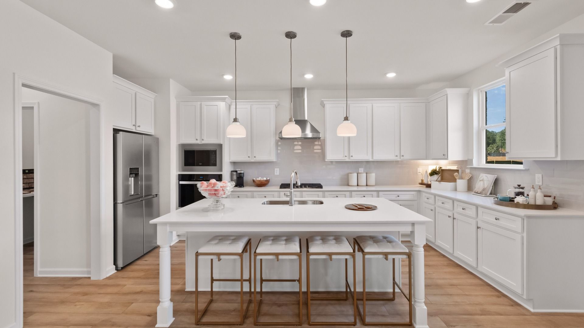 Wagener open-concept kitchen with modern white design, tile backsplash, and oversized island at Burchwood in Stockbridge, GA.