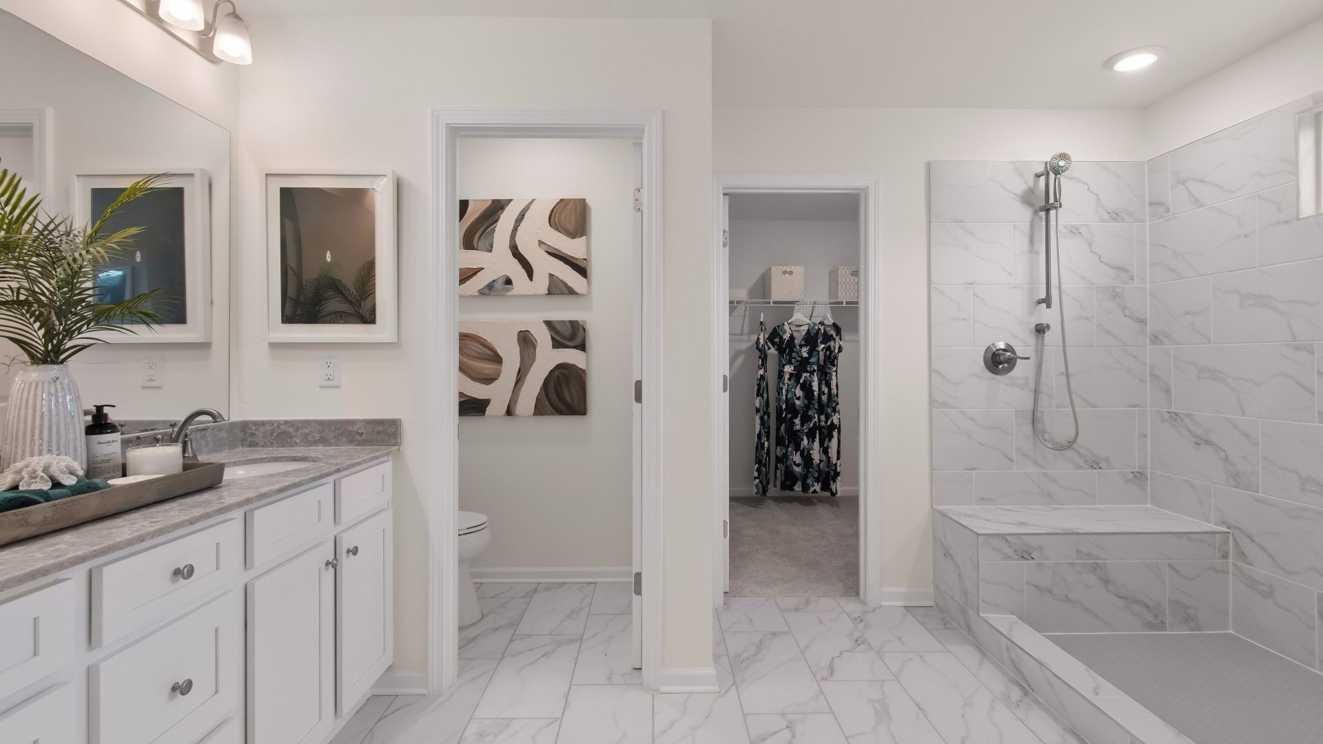 Luxury primary bathroom with marble floors and shower, dual vanities, and walk-in closet in Burchwood in Stockbridge, GA.
