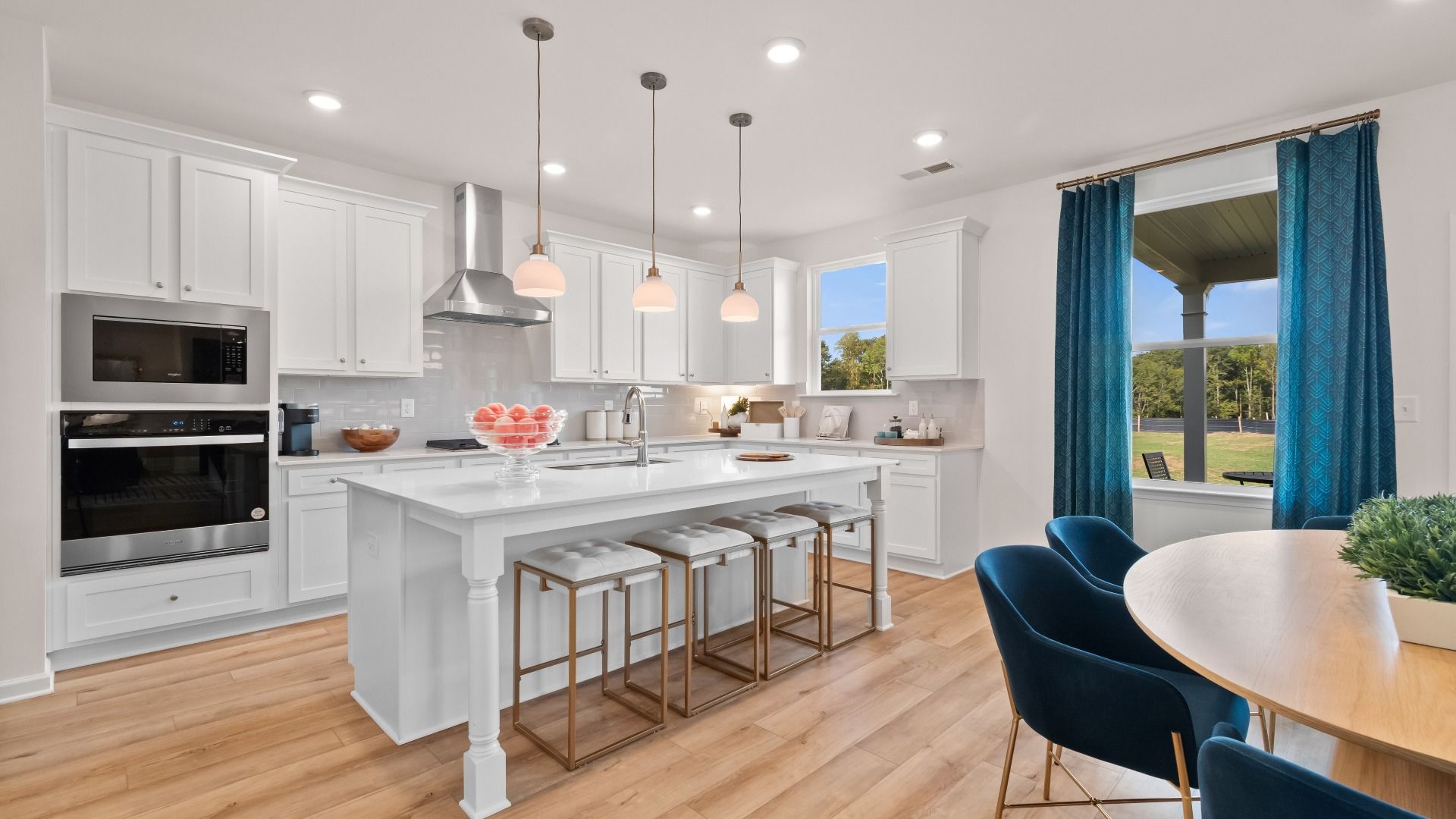 Open-concept Wagener kitchen with oversized island, pendant lighting, and bright white cabinetry at Bowers Farm.