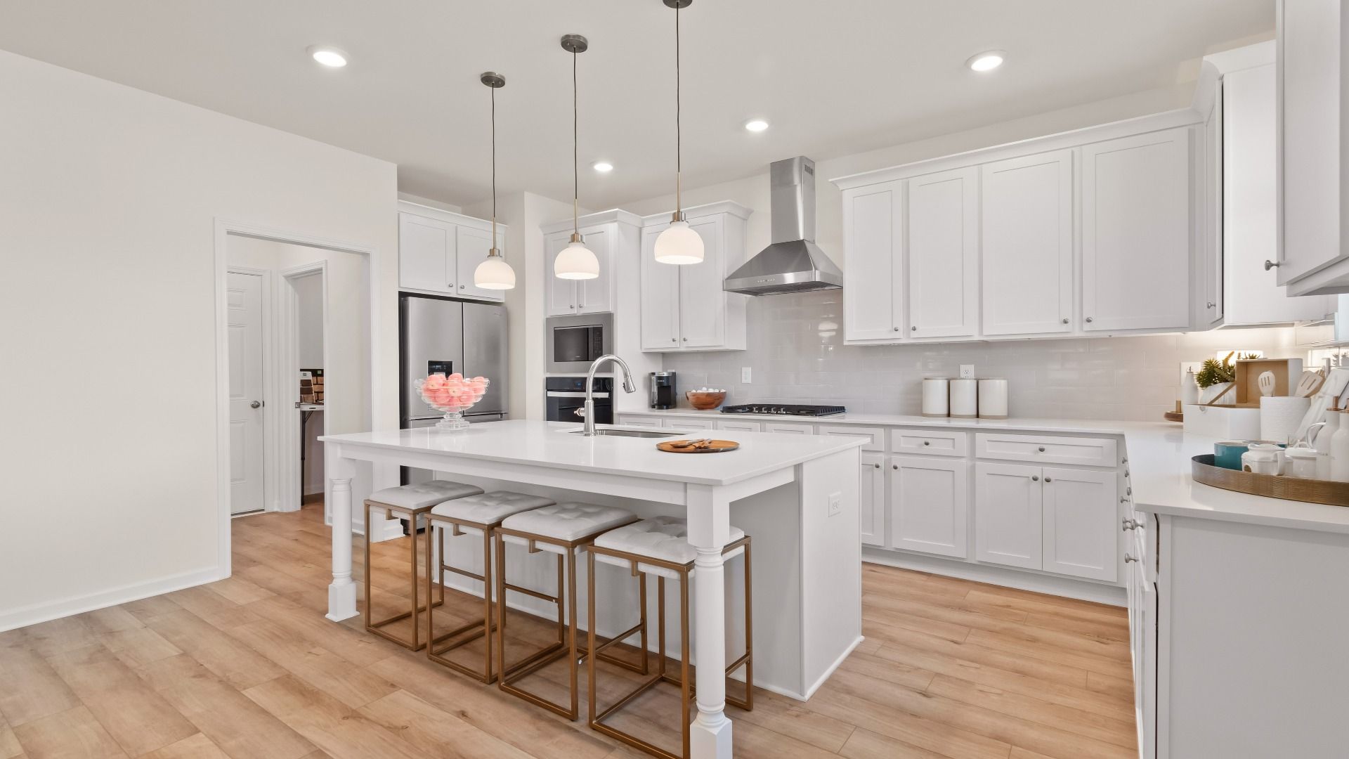 Open-concept Wagener kitchen with clean tile backsplash, white cabinetry, and large island with seating at Bowers Farm.
