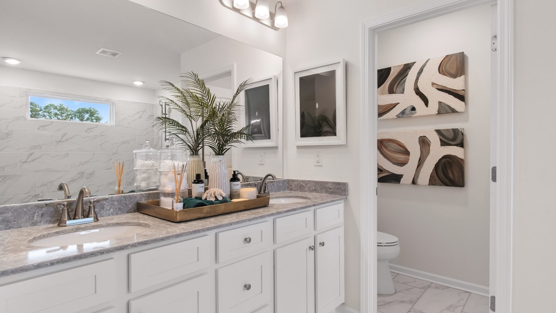 Luxury primary bath with dual vanities and elegant tile floors, and walk-in shower in the Wagener at Bowers Farm.