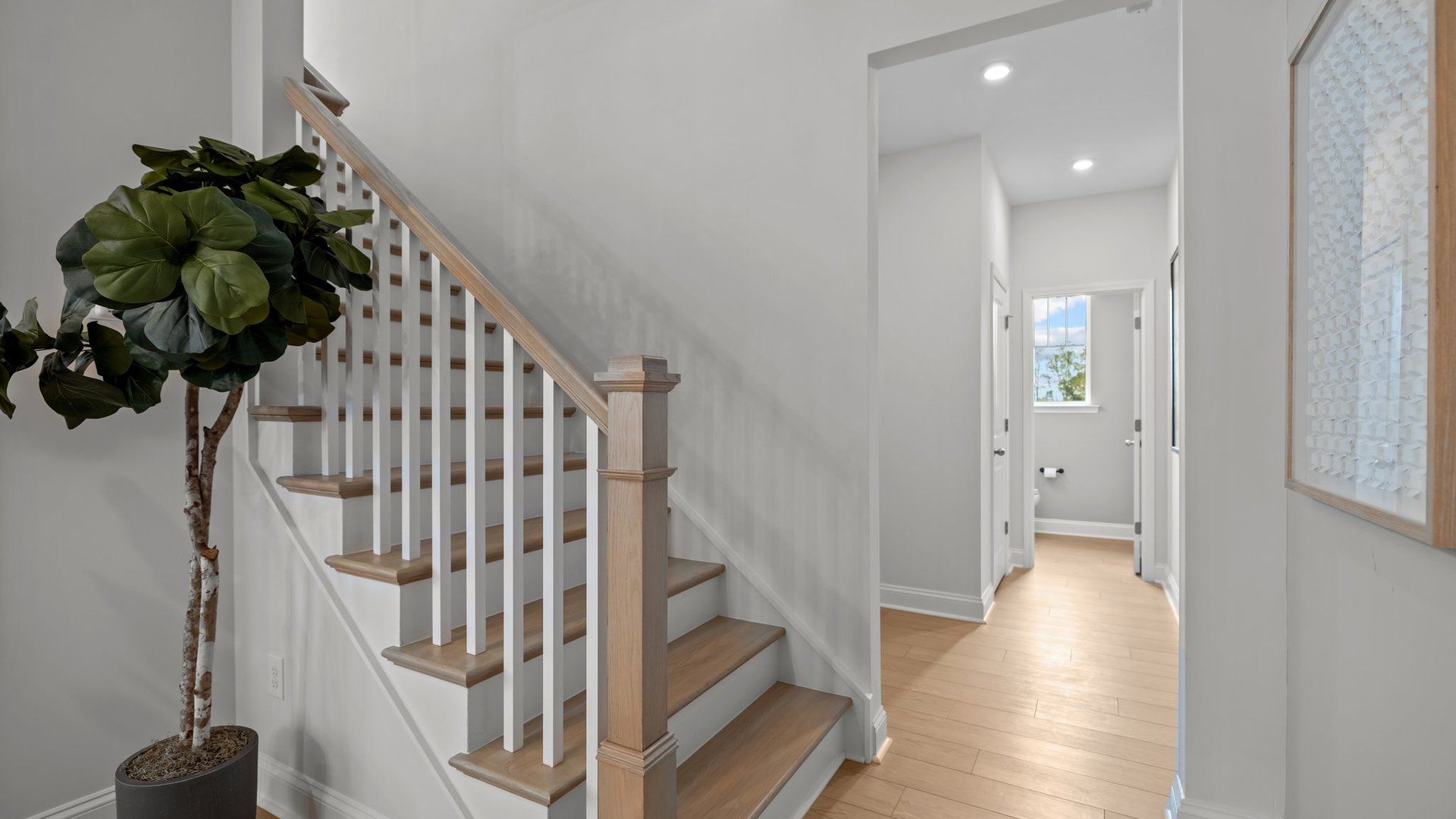 Wide-entry solid oak trads stairs with open rails and premium finishes in the Adaline Design by DRB Homes Charlotte, NC