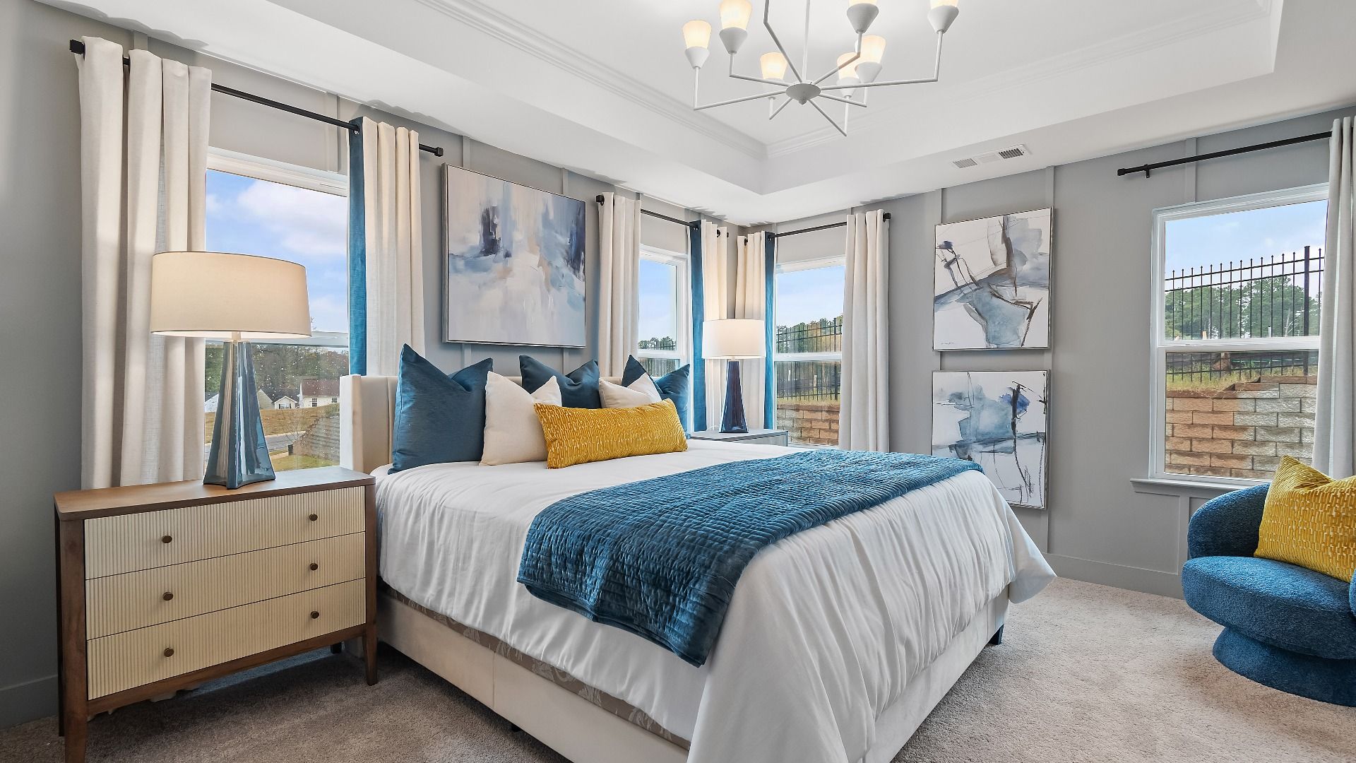 Stylish primary suite in new construction townhome featuring tray ceiling and bright modern palette in Riverdale, GA.