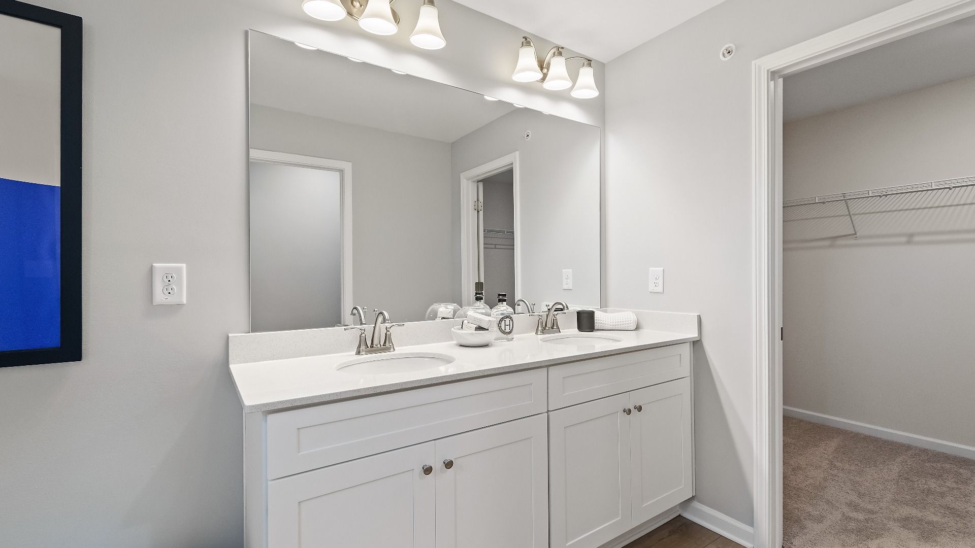 Bathroom with double vanities, quartz countertops, modern fixtures, and large mirror in new townhome at Auburn Ridge.