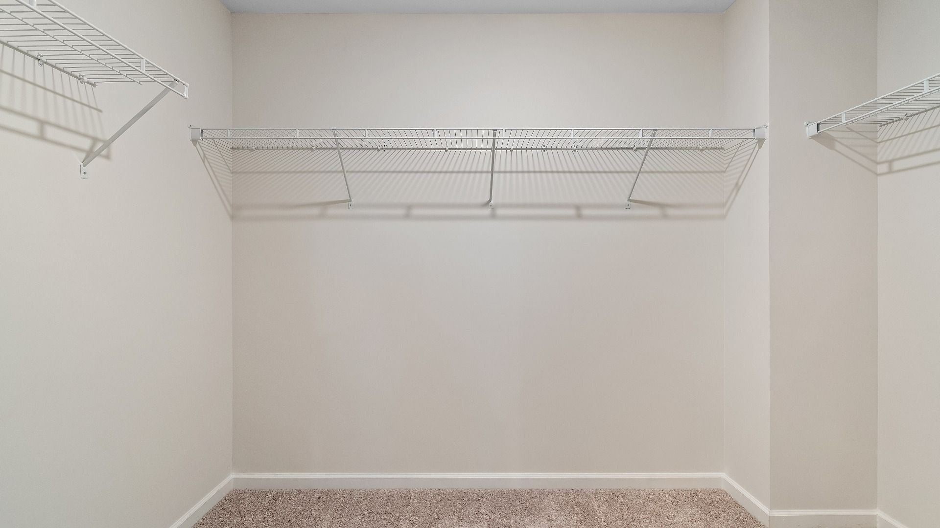 Generous walk-in closet with built-in shelves, hanging rods, and storage space in new construction townhome.