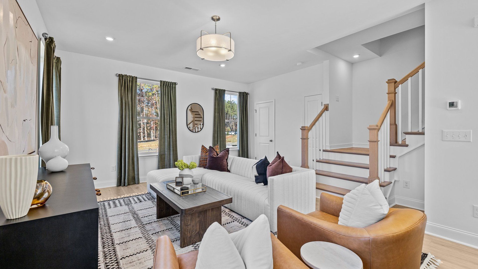 Family room with large windows, elevated ceiling, and wide oak tread stairs with open rails, by DRB Homes Charlotte, NC