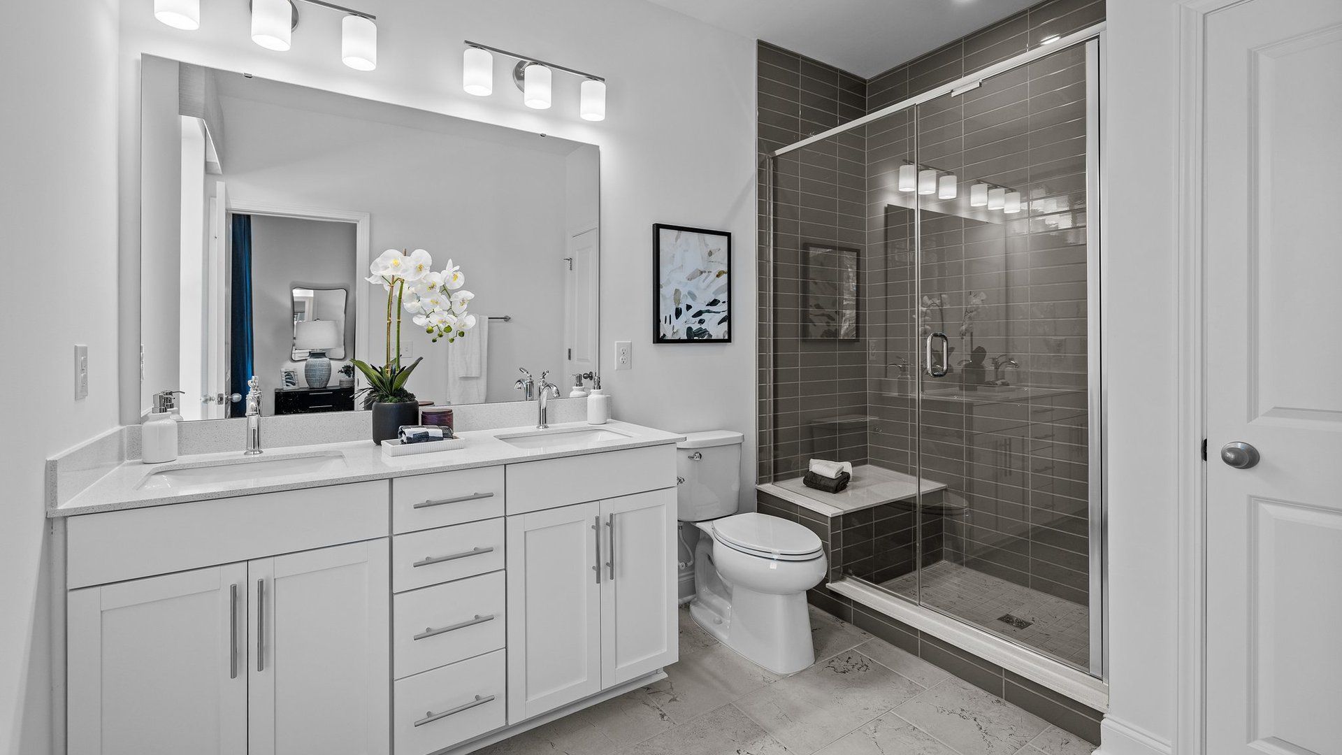 Bathroom with fully tiled walk-in shower with seat and comfort-height 35" cabinets with dual undermount sinks by DRB Homes