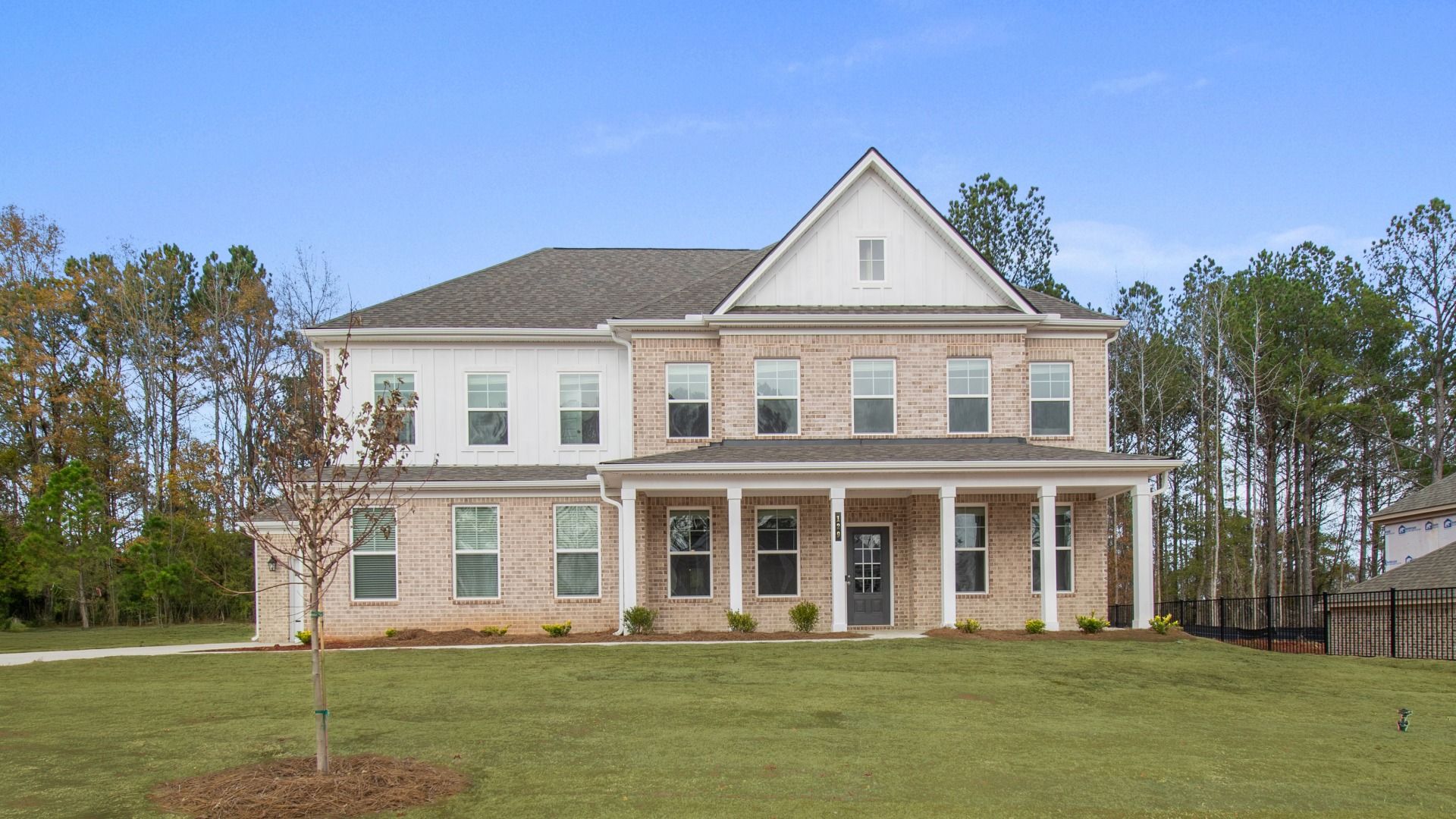 Stonefield brick exterior home with siding accent, covered entry, and side-entry garage at Trinity Park in McDonough, GA.