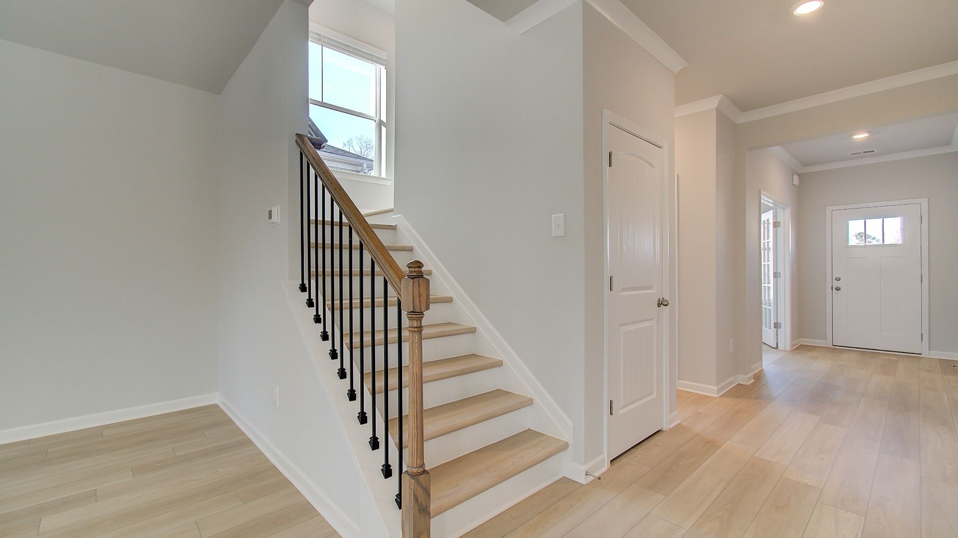 Open foyer and staircase with  LVP flooring and open railing in Pelham home at Bowers Farm in McDonough, GA.