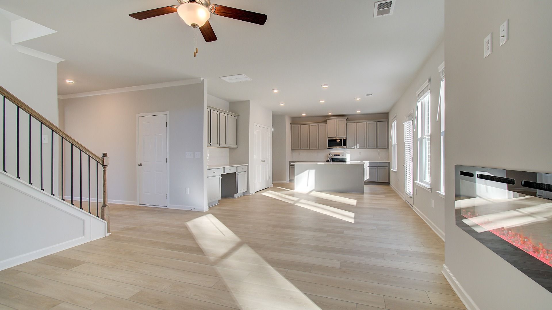 Open-concept Pelham family room with LVP flooring, electric center fireplace, and natural light at Bowers Farm.